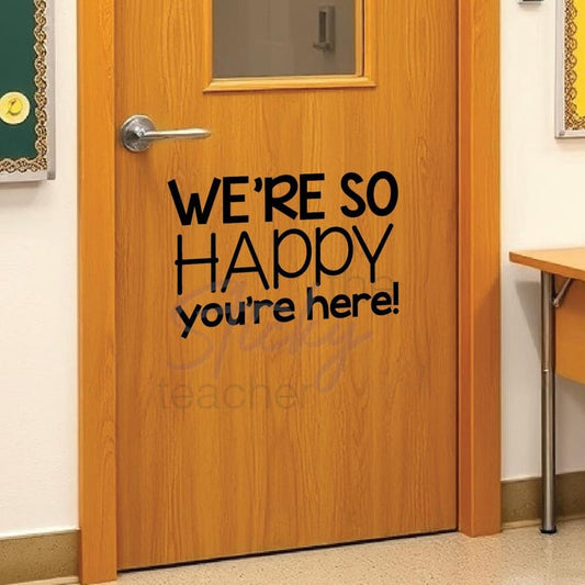 We're So Happy You're Here classroom door vinyl decal on wooden door with small window
