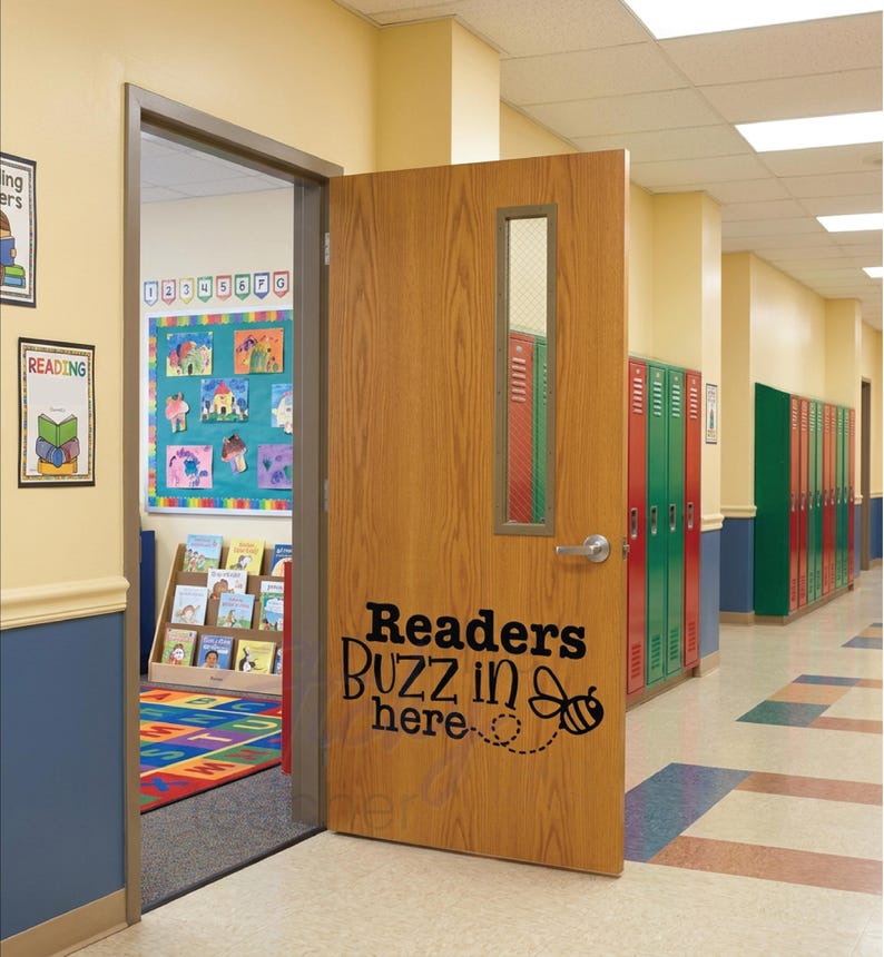 Readers Buzz in Here classroom door vinyl decal on wooden door with colorful lockers and reading corner visible