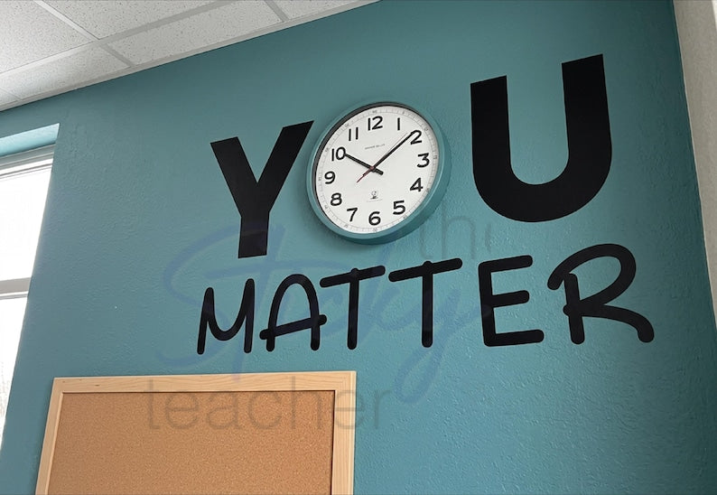 YOU MATTER clock vinyl decal on teal wall with teal-framed white clock as the letter O