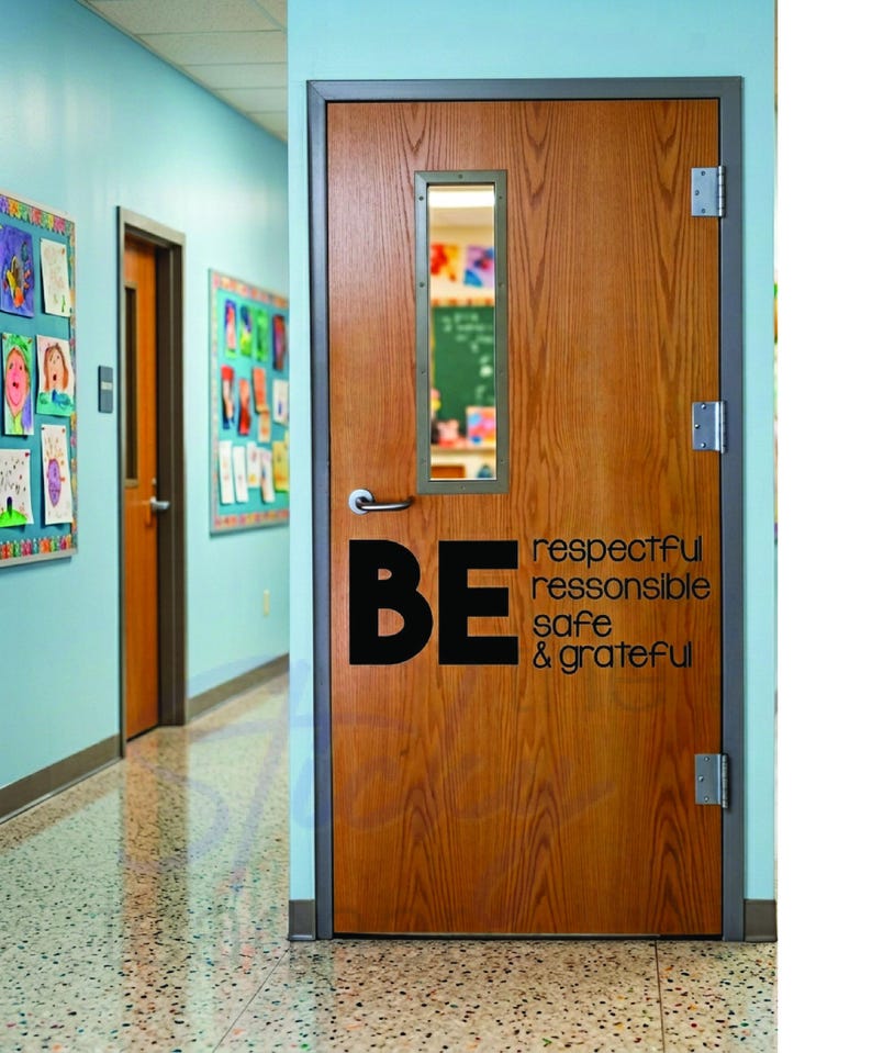 BE respectful responsible safe grateful decal on wooden door in blue school hallway